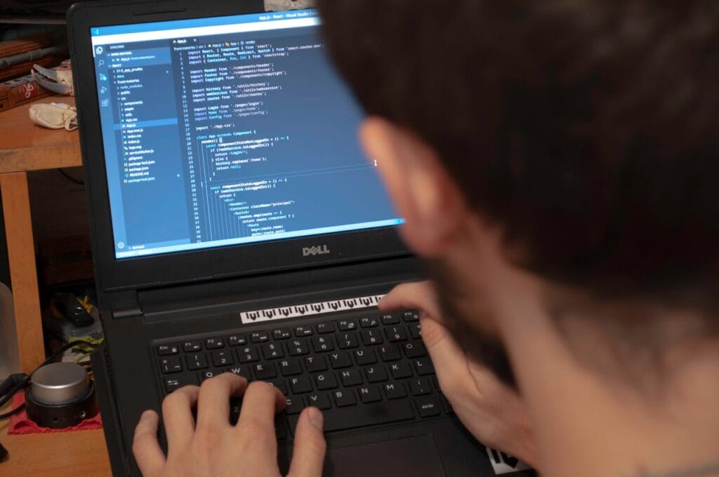 pexels-photo-4078342 Close-up view of a programmer typing code on a laptop in a workspace.